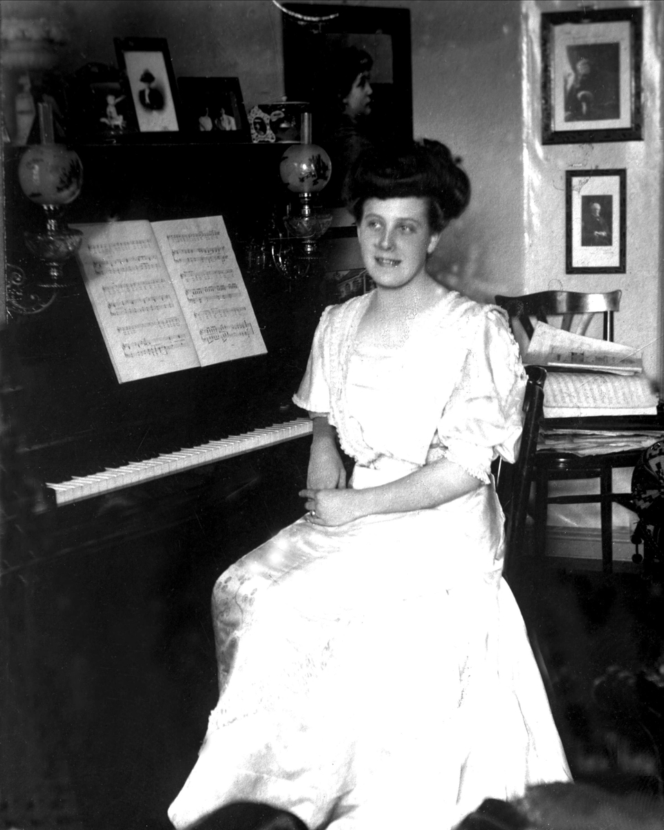 Gustav Borgen, Avfotografering. Portrett, kvinne i interiør, sittende ved piano. Avfotografert 1915.