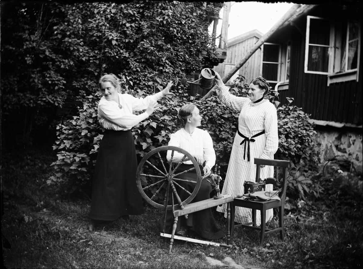 Skötsner-Edhlund, Kvinnor i svarvare Holms trädgård med spinnrock och vattenkanna, Östhammar, Uppland