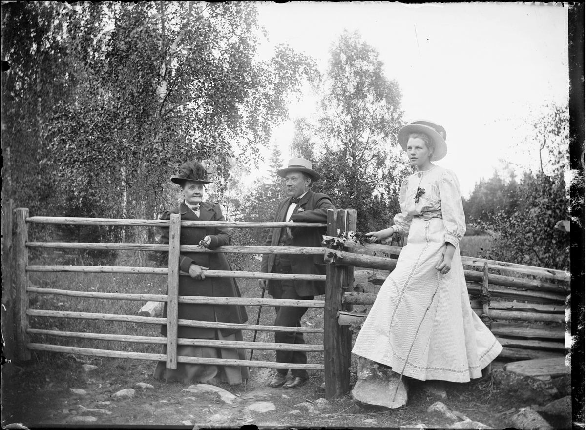 Skötsner-Edhlund, Handlare A G Borg med fru och dotter vid gärdesgårdsgrind i Sanda, Harg socken, Uppland