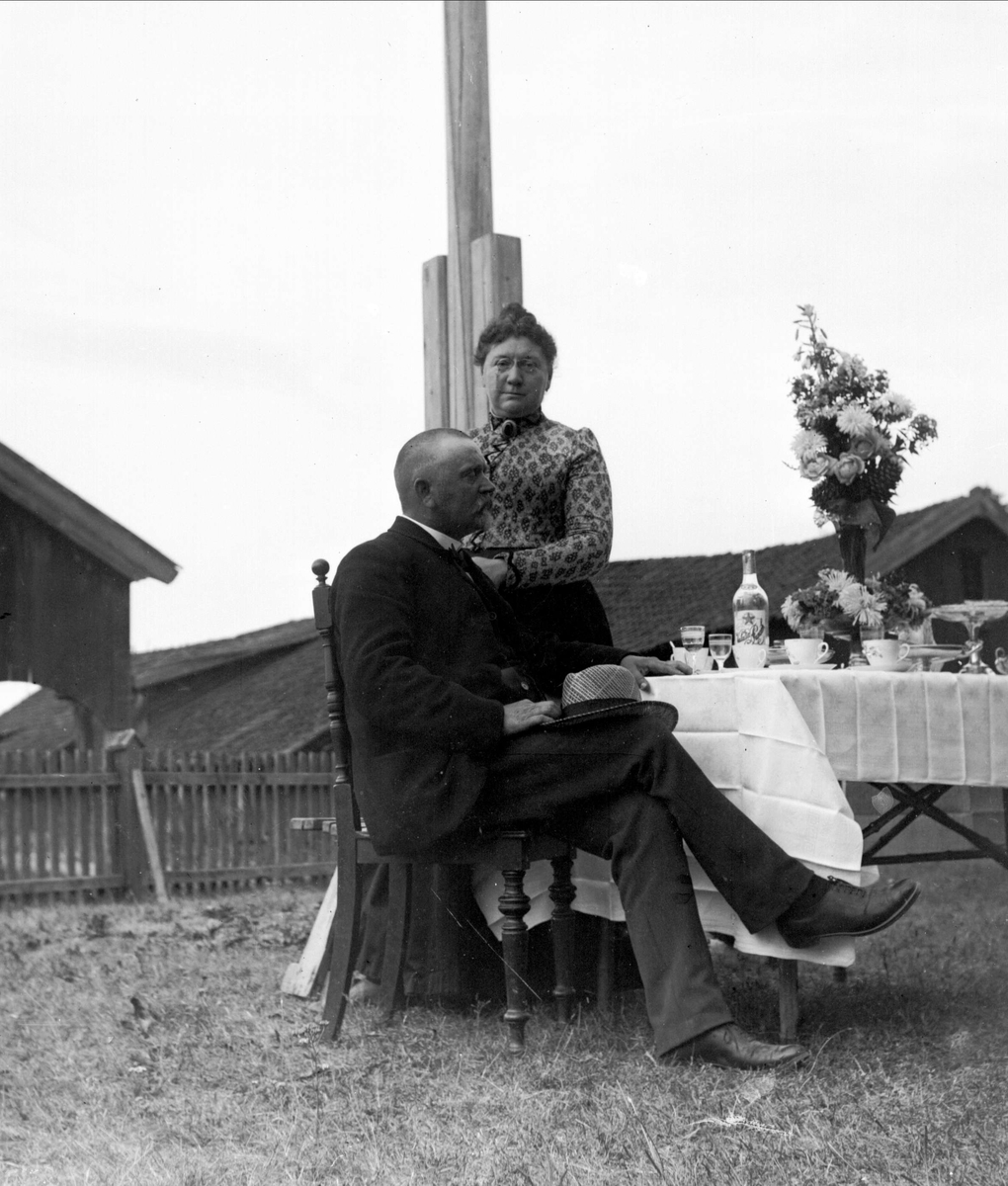 Gustav Borgen, Gruppeportrett, mann og kvinne ved bord i hagen. Vinhandler Larsen m/frue, fra Bygdøy.