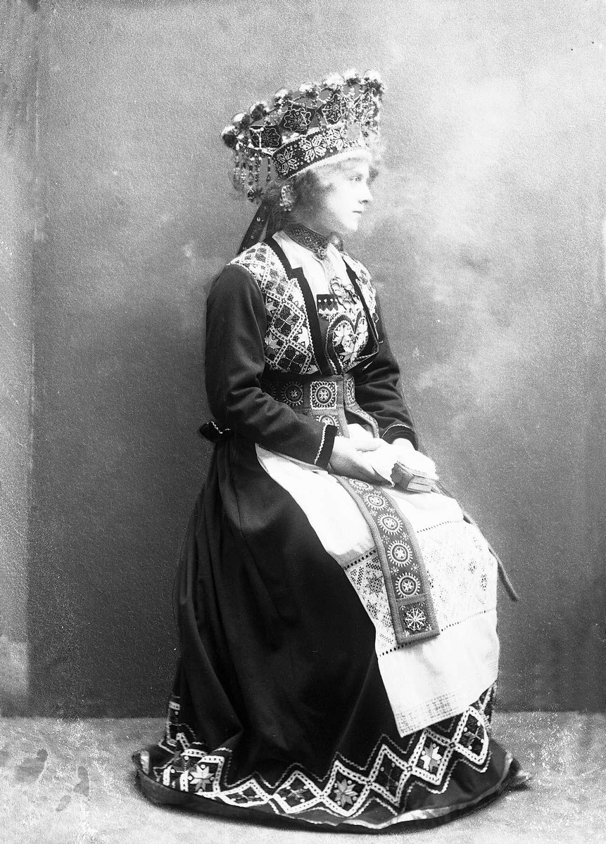 Solveig Lund, Studiofotografi av kvinne med brudedrakt og brudekrone. Holder på salmebok/bibel. Sittende helfigur. Vendt mot høyre. Ser ut mot høyre.