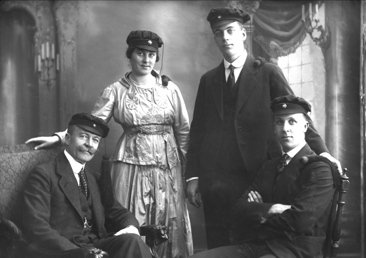 Gustav Borgen, Gruppeportrett, far med tre voksne barn, alle fire med studentlue. Familien Dammann, Axel, Kirsten, Aage og Rolf.