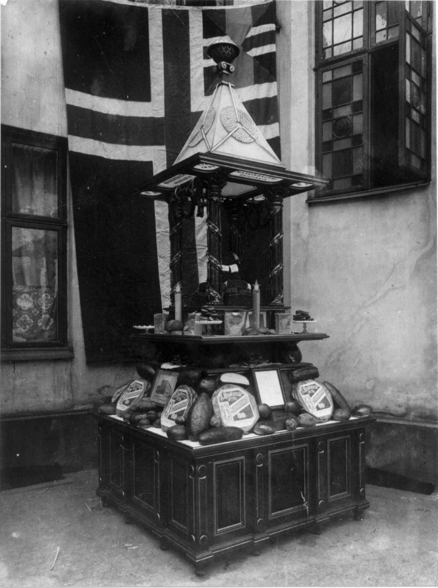 Narve Skarpmoen, A. Hansens Bakeri, Universitetsgata 8, Oslo, ca.1896. Utstillingsmonter, oppsatt til prøve i gården, merk unionsflagget.