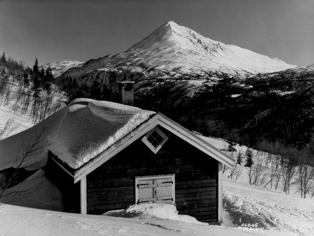 Anders Beer Wilse, Landskap ved Gaustatoppen med hytte eller seter i forgrunnen. Snødekte fjell.