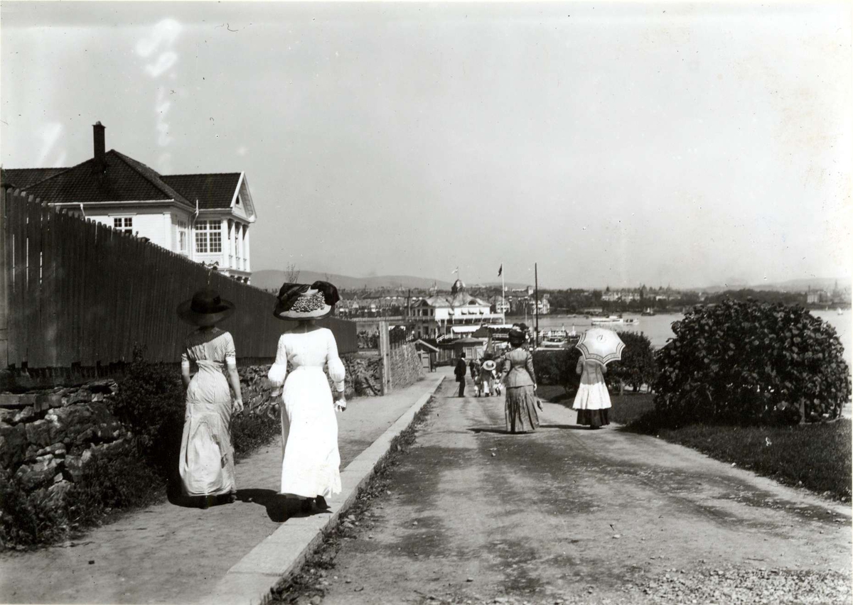 Hermann Christian Neupert, Bygdøy, Oslo 1911. Kvinner spaserer mot restaurant Dronningen. Fotside antrekk. Alle med hatter.
