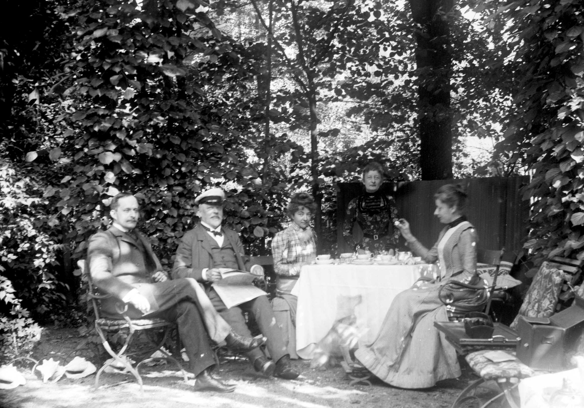 Juliane Fredrikke Langberg, Familiegruppe i hageselskap med dekket kaffebord. Sigrid f. Holm (usikkert om hun er en av de tre kvinnene t.h.), fotografens niese, hos sine svigerforeldre (fam. Hudtwalcker) i Blankenese, Hamburg. Mannen Heinrich (Heini) sitter t.v., deretter svigerfaren. Fra malerinne Juliane Fredrikke Langbergs…