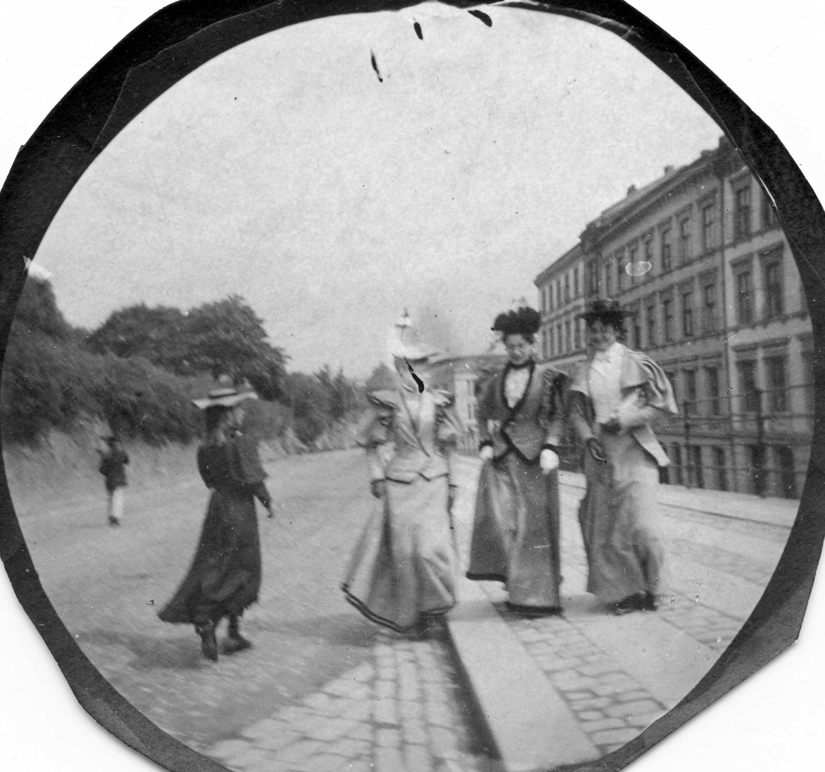 Fredrik Carl Mülertz Størmer, Fire unge kvinner spaserer i bygate, Oslo, tre vendt mot fotografen. Bygårder på den ene siden av gaten bak smijernsgjerde, park på den andre.