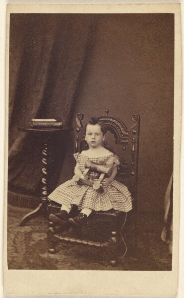 Unknown, [Unidentified little girl holding a toy wooden horse, seated]