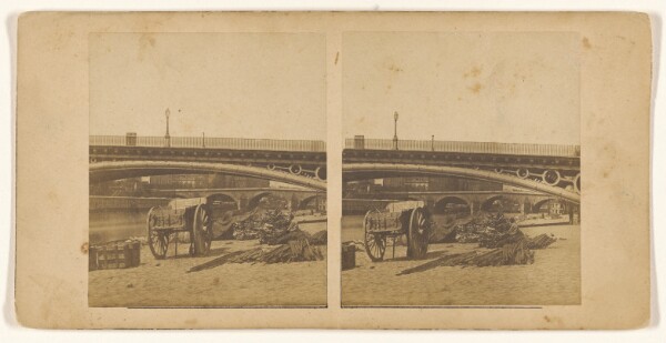 Unknown, [Empty wagon, materials on ground near riverbank]