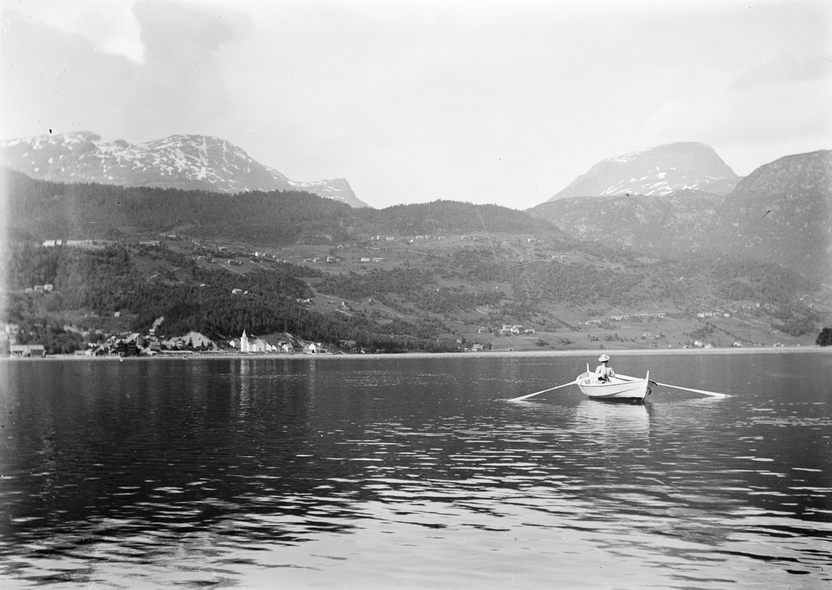 Okänd,, Kvinna ror med roddbåt på vatten, berglandskap i bakgrunden, sannolikt i Norge