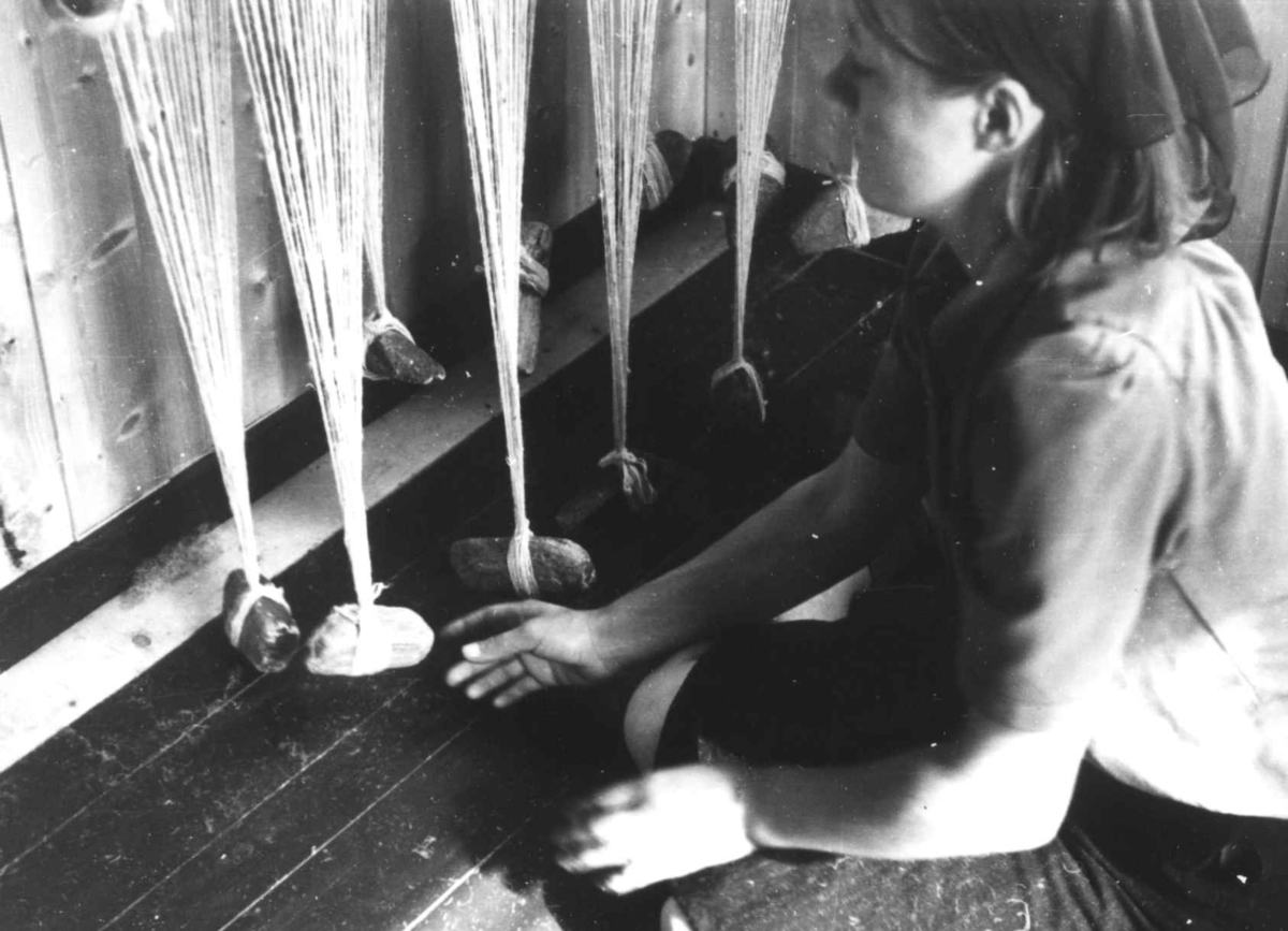 Anna Grostøl, Greneveving. En kvinne sitter foran renningen med steinlodd. Lyngen, Troms 1947.