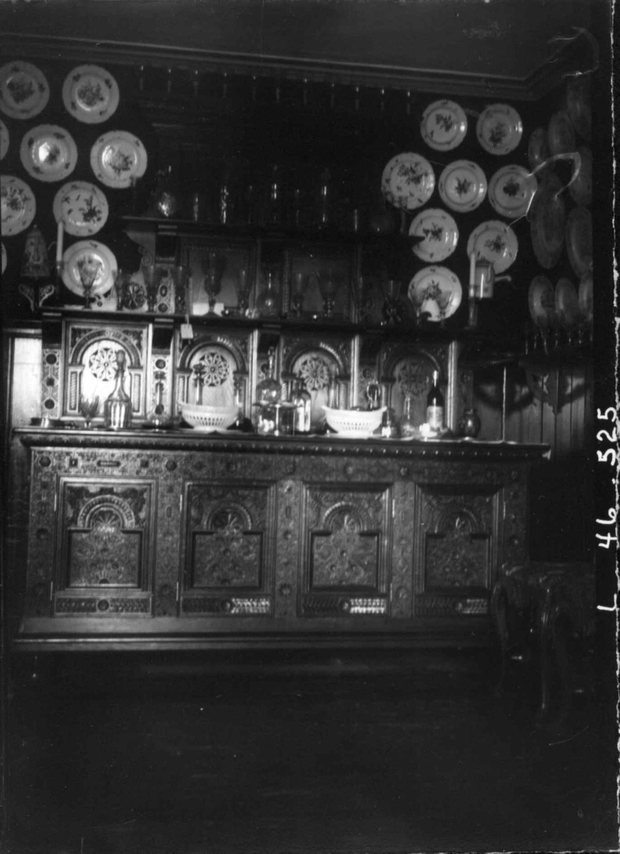 Fredrik Emil Faye, Interiør, Dal gård, Ullensaker. Buffet med dekketøy og flasker, tallerkner i keramikk hengt opp, ca. 1898. Fra serie fotografert av kammerherre Fredrik Emil Faye (1844-1903), gårdens eier.