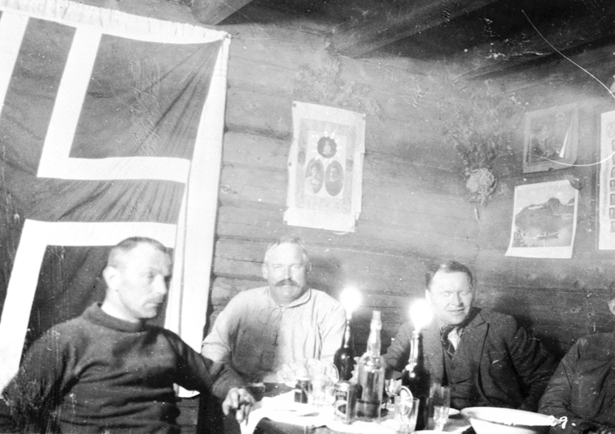 Anno Domkirkeodden, Interiør, hytte på Nysætra, Ringsakerfjellet. Tre menn feirer kronprins Ola og kronprinsesse Märthas bryllup. Fra venstre er Grinaker, Nielsen, Aksnes.