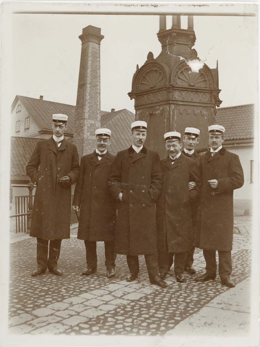 Okänd,, Six men, Harald Falk second from left, dressed student caps and rock, at St Erik’s well, Uppsala around 1900