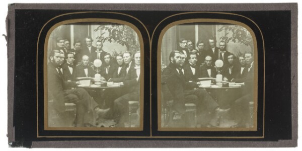 Unknown, [Group of men seated around a table, lamp at center of table]