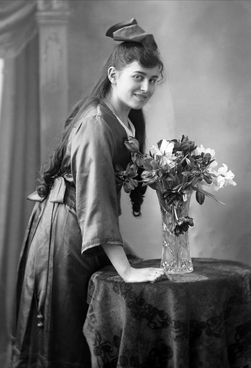 Gustav Borgen, Portrett, ung pike i mørk drakt, ved bord med blomst. Inger Lange.