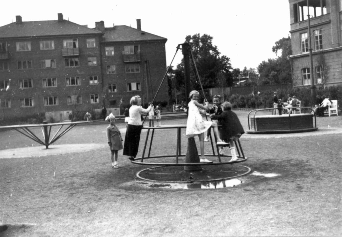 Hermann Christian Neupert, Barn i lek på en lekeplass. Voksne følger med. Boligblokker i bakgrunnen