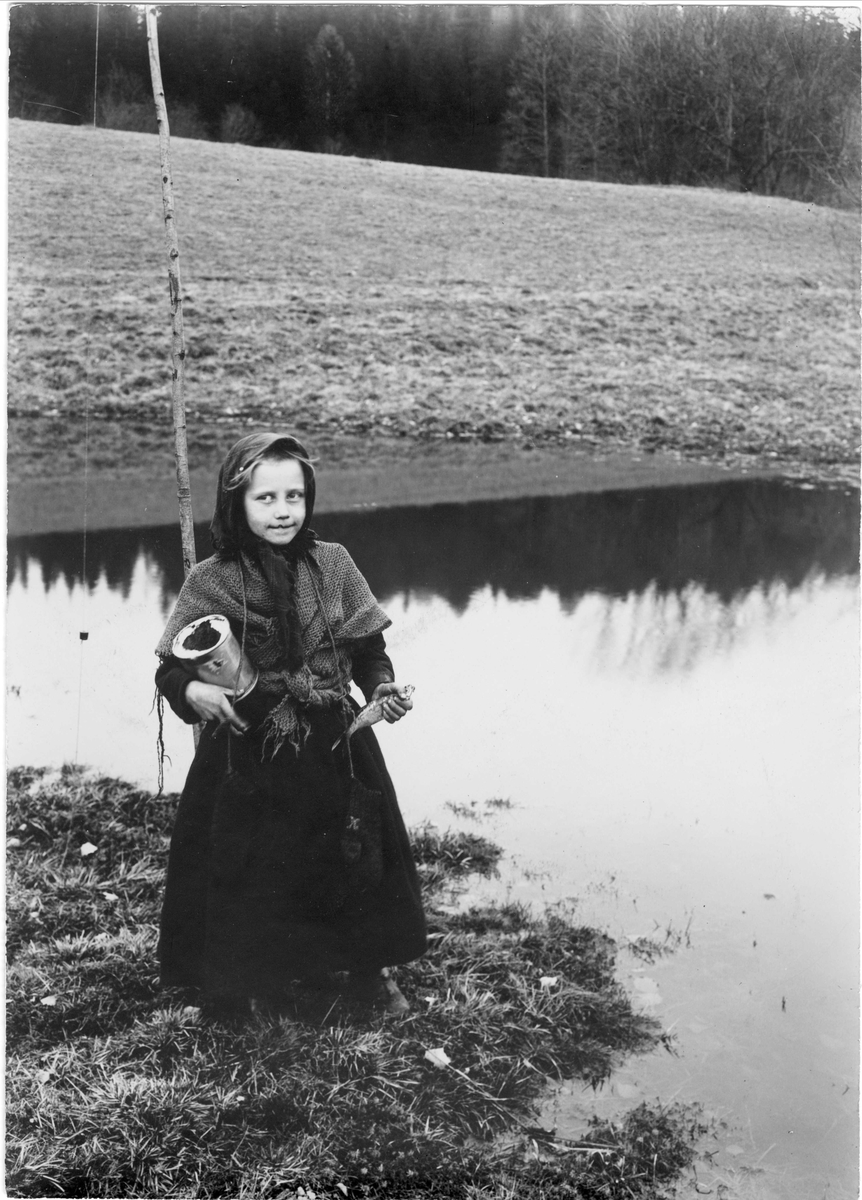 Robert Collett, Pike med med fiskestang, fisk og blikkboks ved elv, ukjent sted. Serie tatt av Robert Collett (1842-1913), amatørfotograf og professor i zoologi.