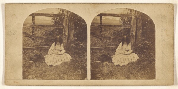 Unknown, [Little girl seated in grass by a fence, reading]