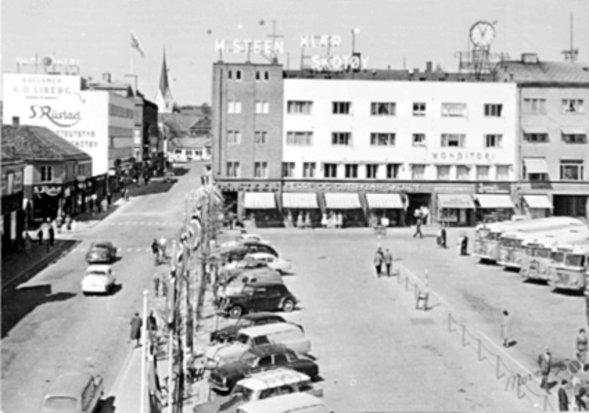 Anno Domkirkeodden, OVERSIKT ØSTRE TORG MED TORGGATA. PARKERINGSPLASSEN MED BILER OG BUSSER, KLOKKA M. STEENS GÅRD, BALLONGER