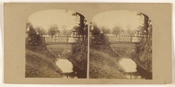 Unknown, [Woman crossing footbridge over stream]