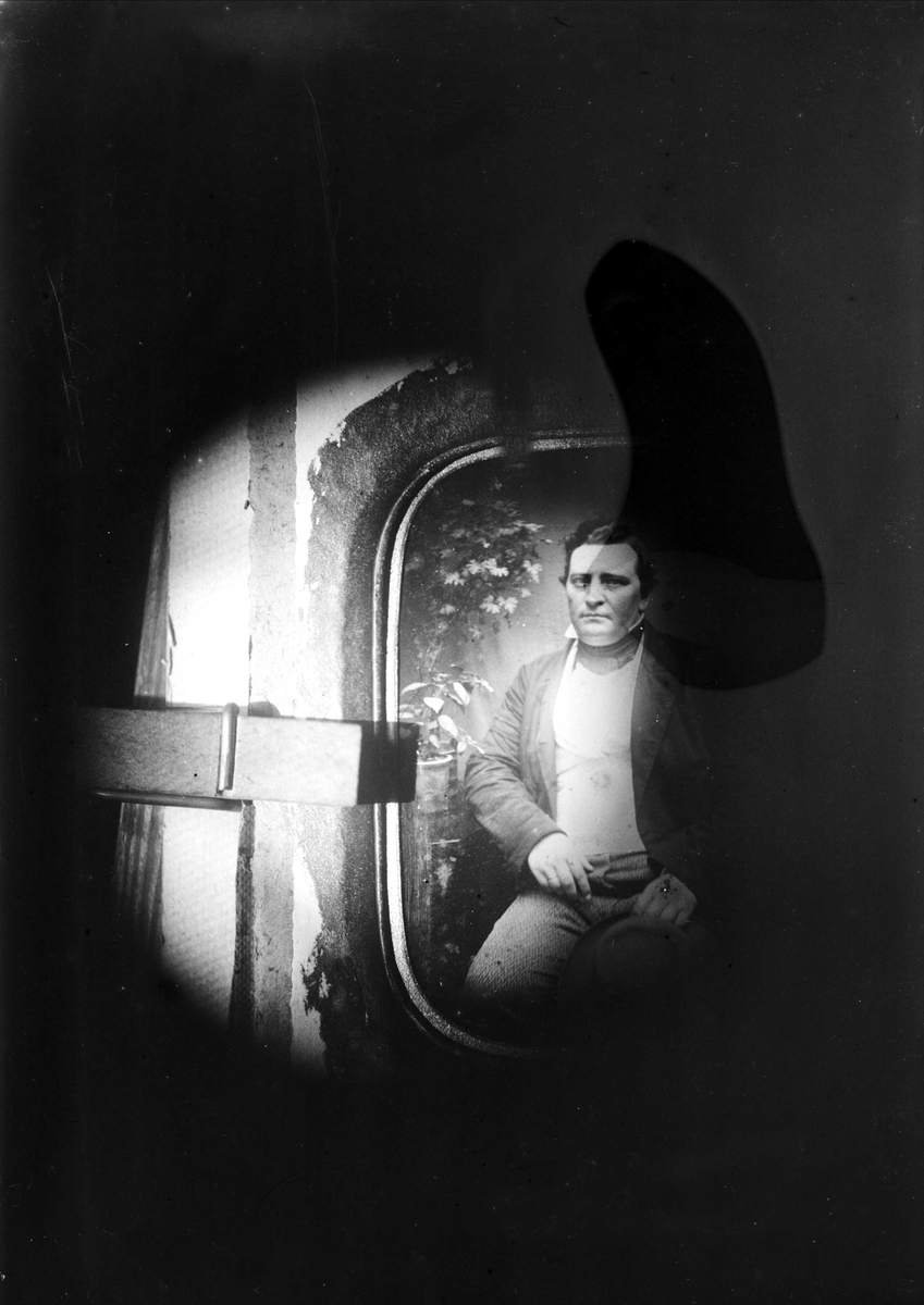 Juliane Fredrikke Langberg, Motivet er et bilde av et eldre fotografi i ramme, et portrett av en sittende mann. Ukjent. Motivet er i en sirkel med mørke flater omkring. Fuktskadet. Fra malerinne Juliane Fredrikke Langbergs (1856-1930) samling, tatt ca.1895-1910 med motiver fra slekt og venner samt steder tilknyttet samvær med…