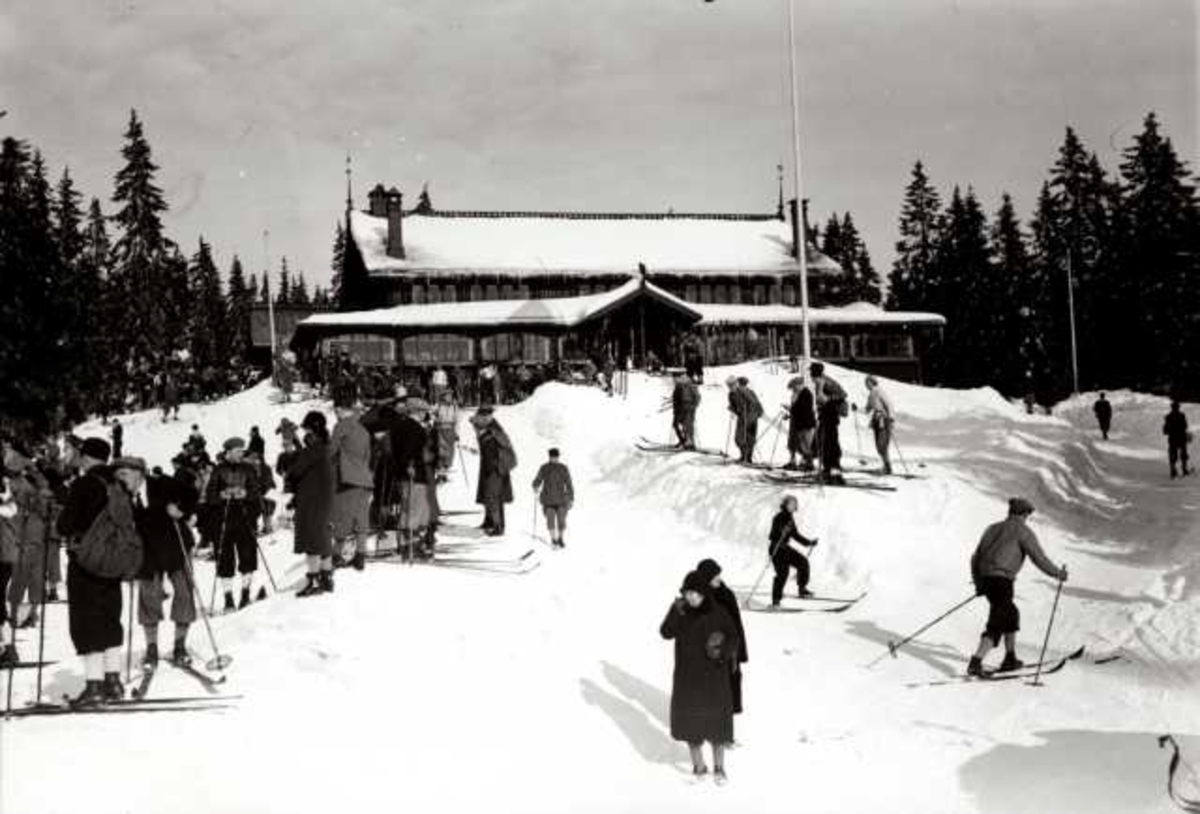 Hermann Christian Neupert, Frognerseteren Restaurant, Nordmarka, Oslo. Vintermotiv. Mennesker på ski foran resturanten.