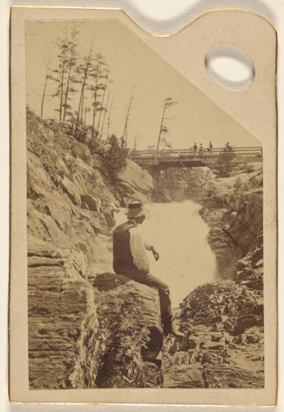 Unknown, [Unidentified man sitting on rocks near a waterfall]