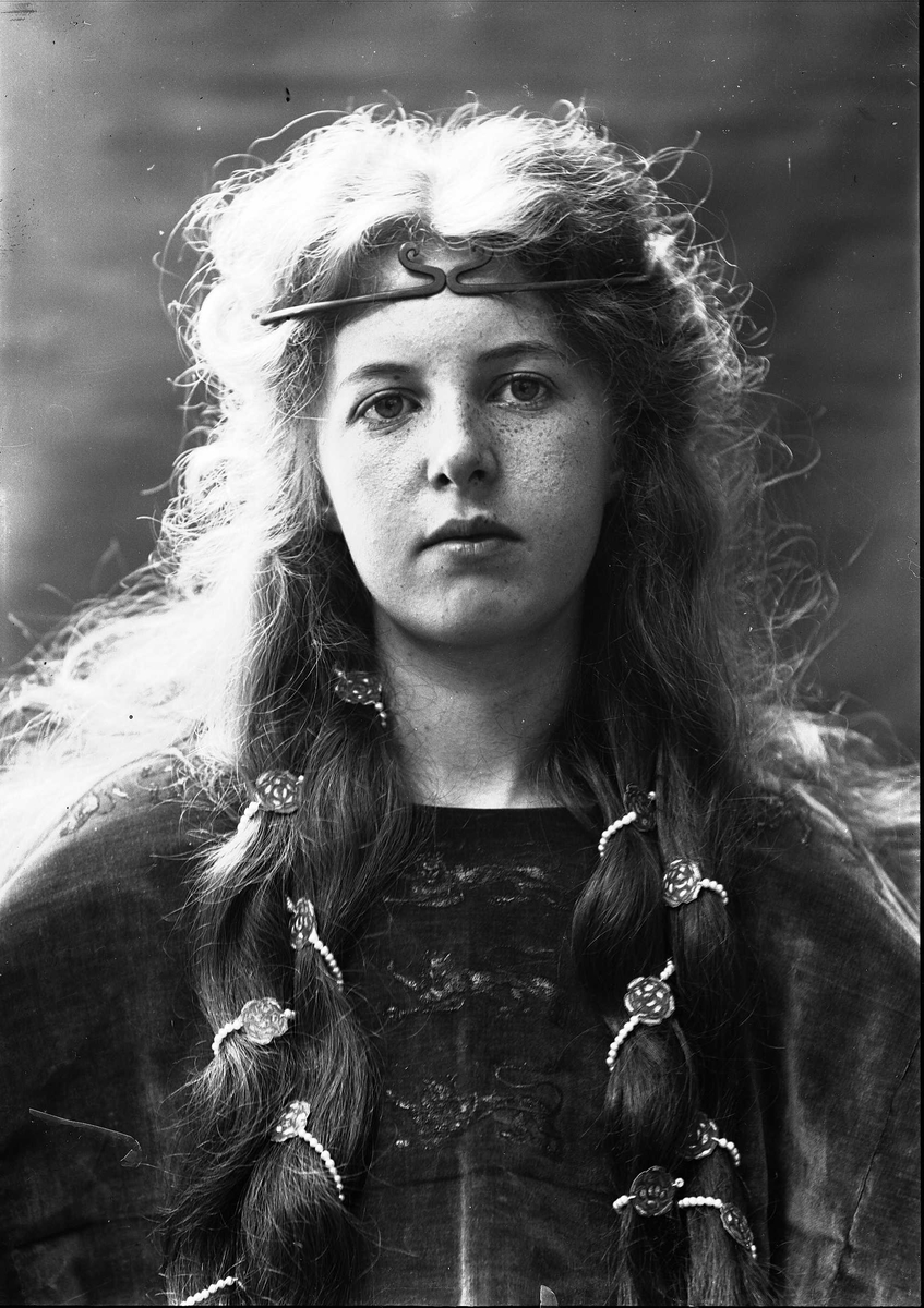 Solveig Lund, Brystportrett av kvinne i drakt med riksvåpen og hårsmykke.