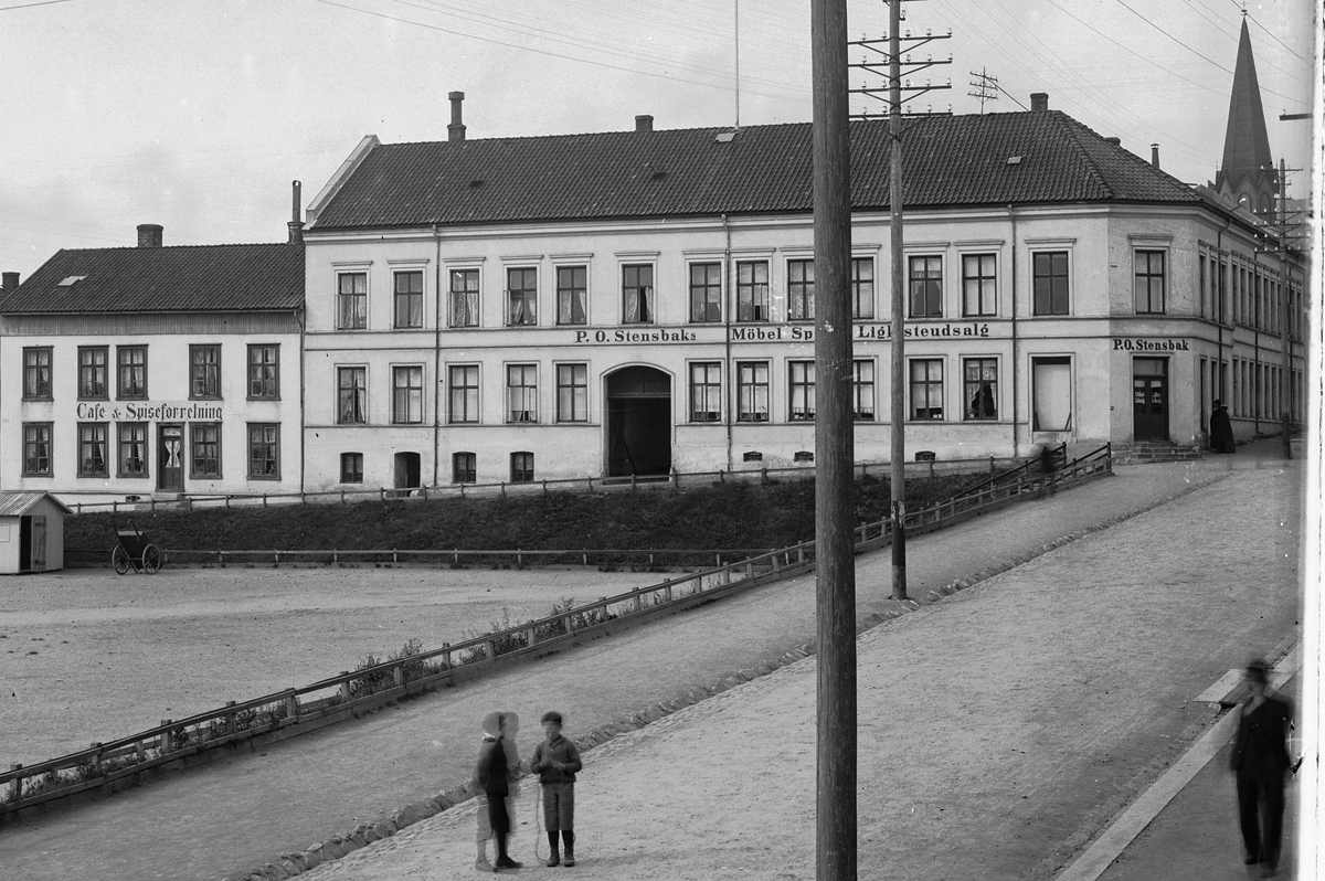 Hans Emil Erichsen, Østre Torg i Hamar med Grønnegata og Håkons Gate. Folk på torget. P.O. Stensbak Møbel Speil & Ligkisteutsalg. Cafe & Spiseforretning. Utsnitt.