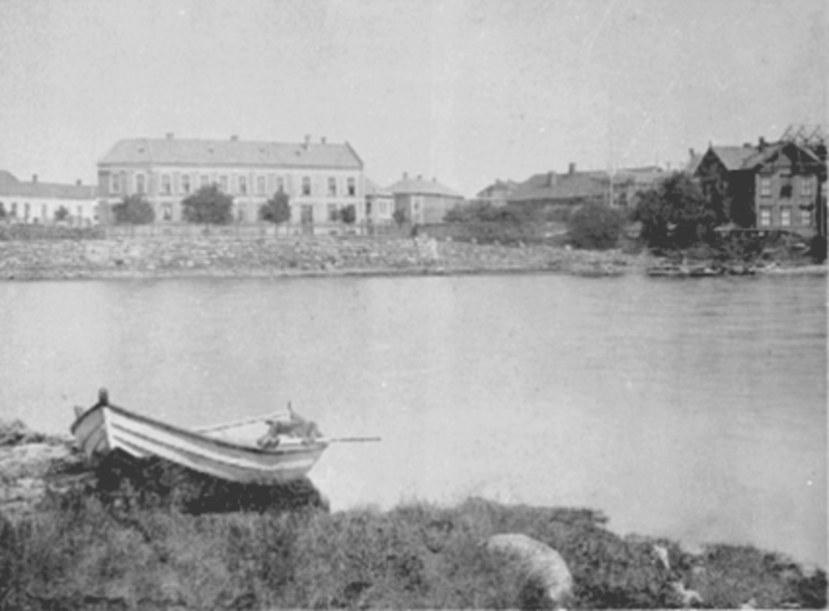 Anno Domkirkeodden, Jernbanehotellet i midten, den gamle Hamar Jernbanestasjon til høyre. Helt til venstre er Wieberggården der Sparebanken Hedmark ligger i dag, og man kan se Grand Hotell under oppføring helt til høyre. Robåt i forgrunnen.
