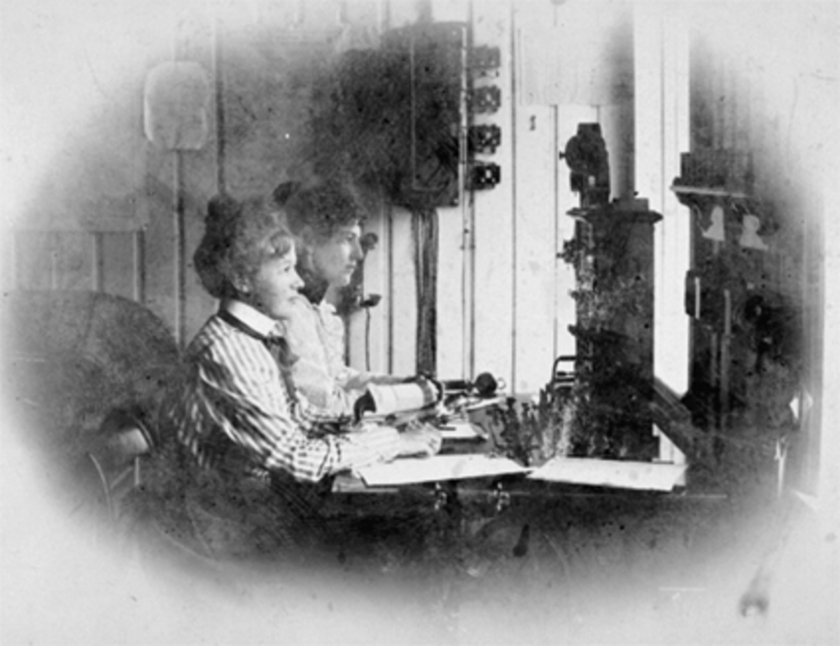 Anno Domkirkeodden, Interiør, 2 telefondamer, Dagny Halvorsen nærmest. Sentralbord i Stangeveien 4. Telegrafen leide lokaler her fra 1881 til 1921. Da flyttet de til Torggt. 13. Fotogr. Grundseth flyttet hit i 1920-åra. Huset revet i 1971. Stangevegen 4 ble bygd i 1881 av telegrafbest. Johannes Halvorsen. Se Hamarboka…
