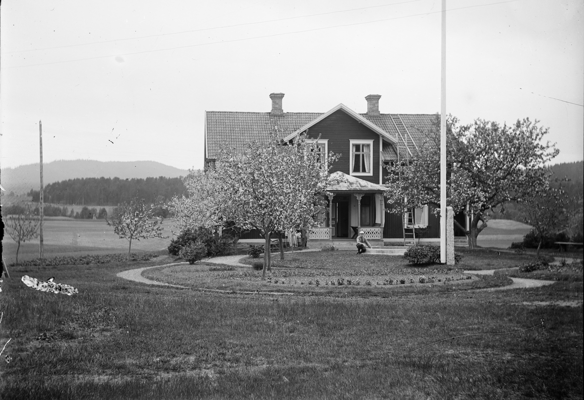 Okänd,, Likely one of Ruben and Christiane Liljefors' sons, sitting in front of residential buildings, likely Svensgården in Dalarna