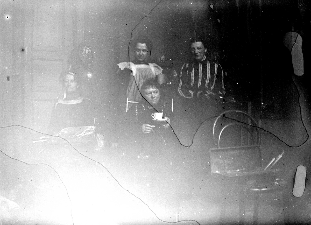 Juliane Fredrikke Langberg, Portrett av malerinnen Harriet Backer, muligens med 3 elever. Hun sitter foran 2 stående kvinner i et interiør med en kopp i hånden. Foran på en wienerstol står en kasse med malersaker. Bildets motiv er svært redusert pga. fuktringer (?). Fra malerinne Juliane Fredrikke Langbergs (1856-1930) samlin…