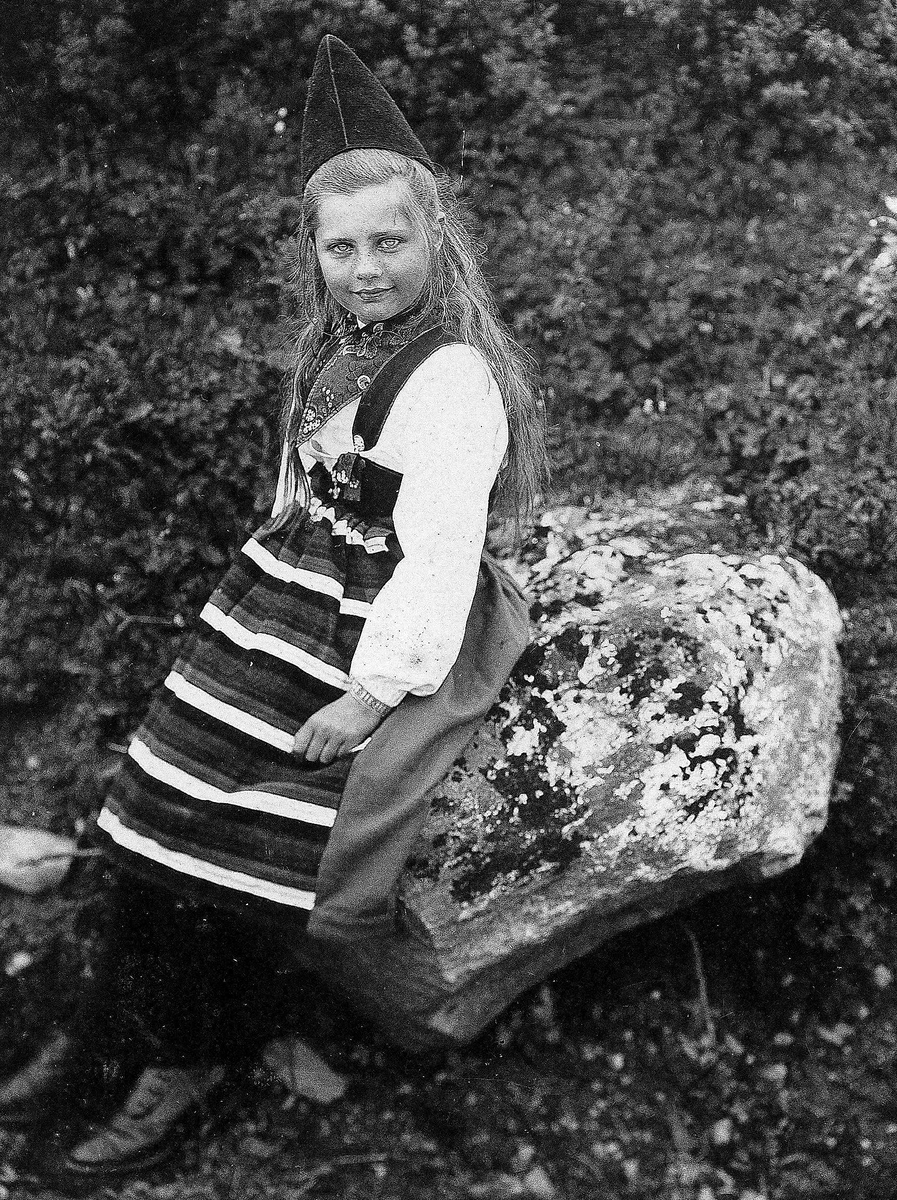 Robert Collett, Pike ved stein, ukjent sted, i drakt fra Rättvik, Dalarne, Sverige. Serie tatt av Robert Collett (1842-1913), amatørfotograf og professor i zoologi.