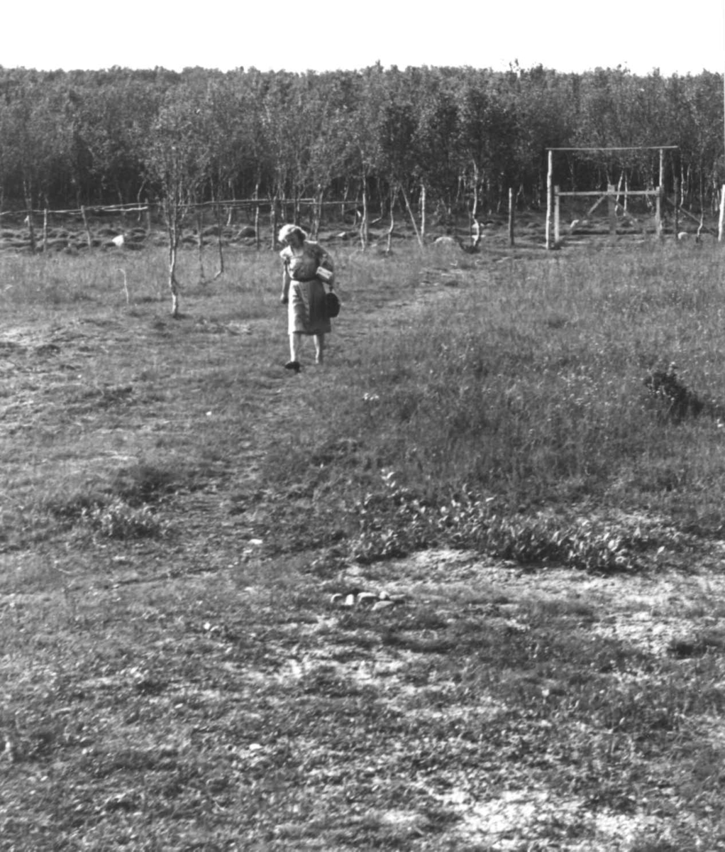 Anna Grostøl, En kvinne spaserer på en sti. Skog i bakgrunnen. Lyngen, Troms 1947.
