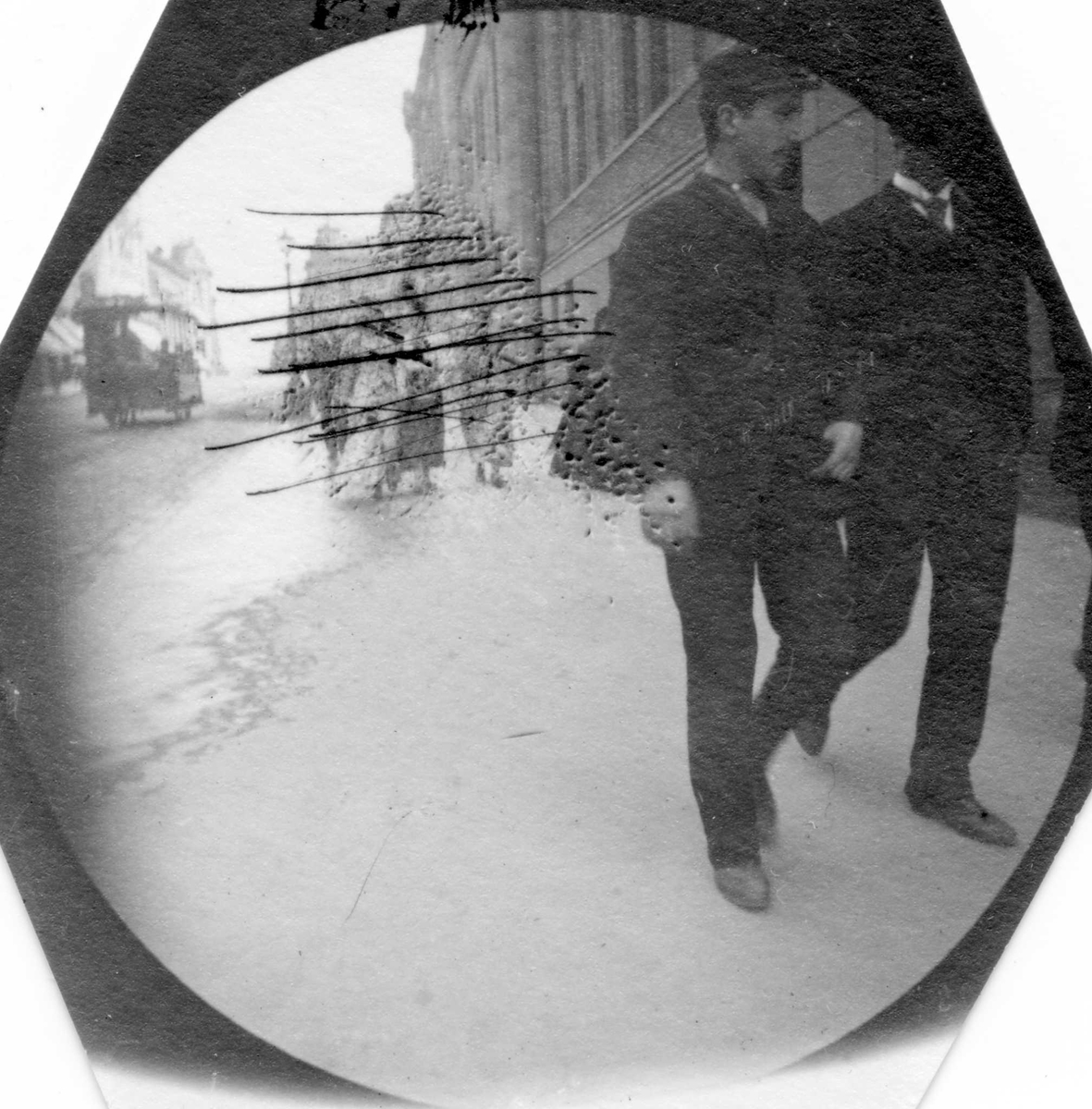 Fredrik Carl Mülertz Størmer, To menn spaserer langs Stortinget på Karl Johans gate, Oslo. Mennesker i bakgrunnen strøket ut. Hestesporvogn.