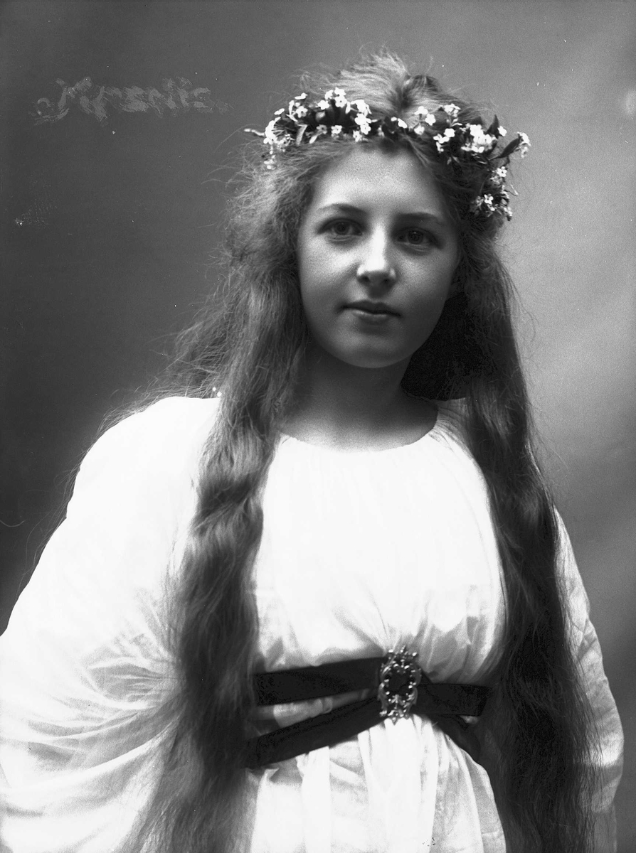 Solveig Lund, Studioportrett av kvinne i drakt med blomster i håret.