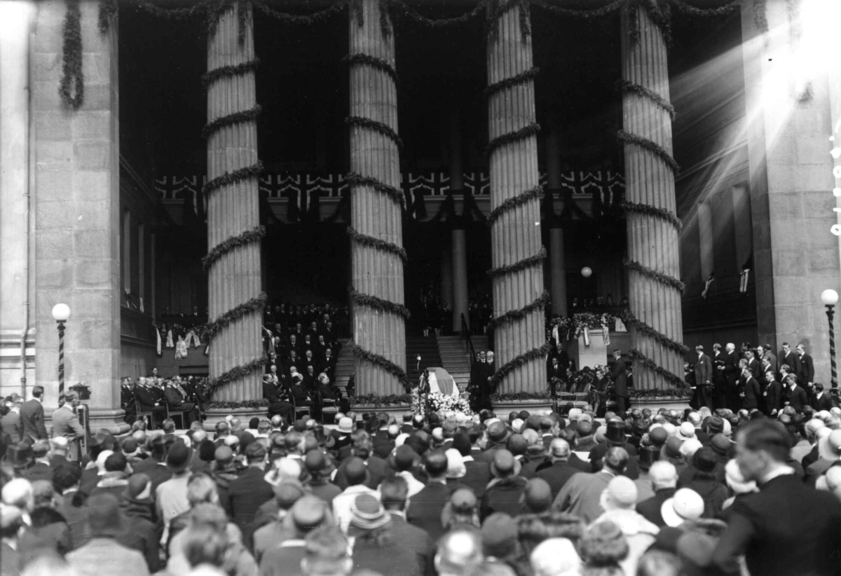 Hermann Christian Neupert, Fridtjof Nansens begravelse 17. mai 1930. Kisten på lit de parade i søylehallen på Universitetet. Søylene dekort med flagg og grønt. Prest eller biskop. Æresgjester. Publikum på Universitetsplassen.