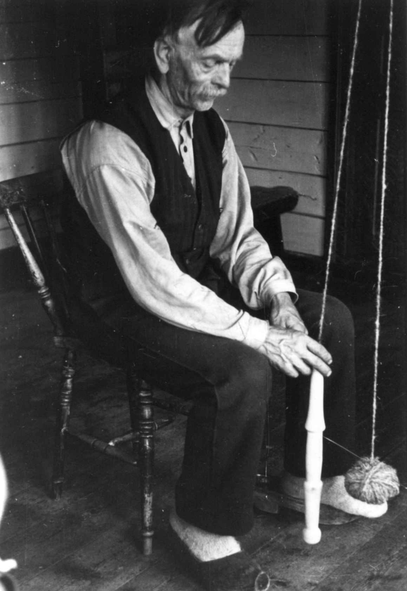 Anna Grostøl, Sigmund Rudlende på Rossevatn spinner på håndrokk. Eiken, Hægebostad, Vest-Agder 1941.