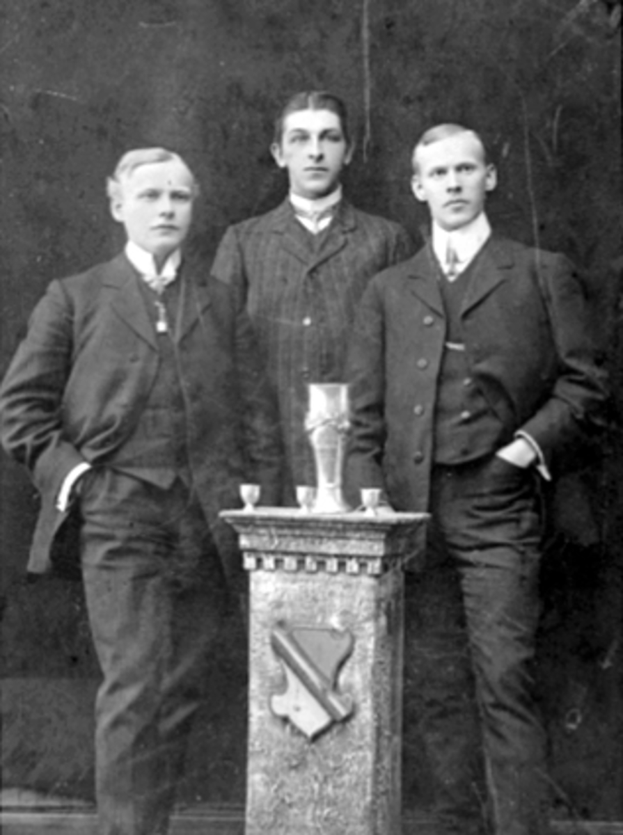 Anno Domkirkeodden, JUNIORPOKAL, HAMAR SKØYTEKLUBB, GRUPPE 3 MENN, SKØYTELØPERE, HARALD MONSEN, HILMAR ERIKSEN OG OTTO MONSEN. HAMAR SKØYTEKLUBBS JUNIORLAG FRA 1909. 21 MARS 1909 ARRANGERTE HAMAR SKØYTEKLUBB DEN FØRSTE JUNIORPOKALKAMP FOR LAGHER I LANDET UTE PÅ MJØSISEN. 1500 TILSKUERE KRANSET BANEN, FINT VÆR MEN DÅRL…