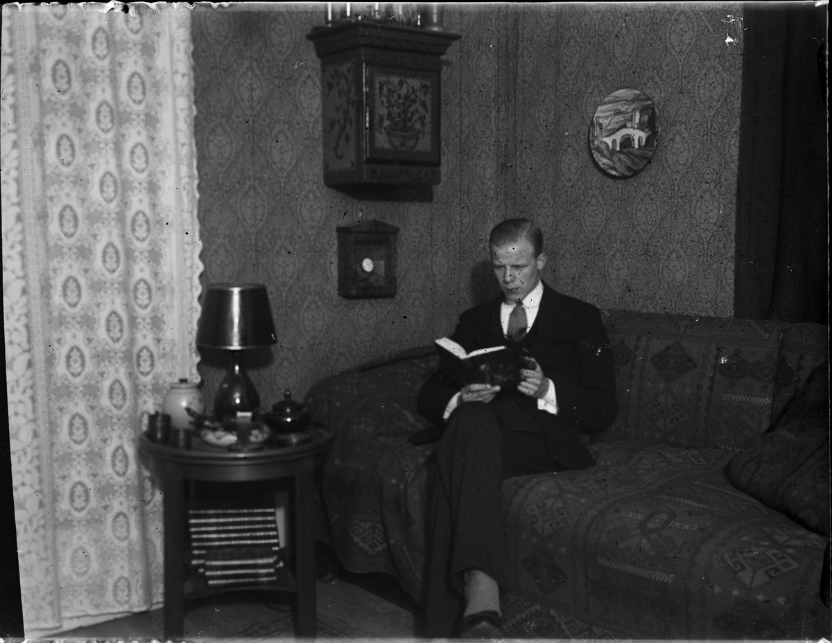Okänd,, Man sitter i en soffa och läser en bok