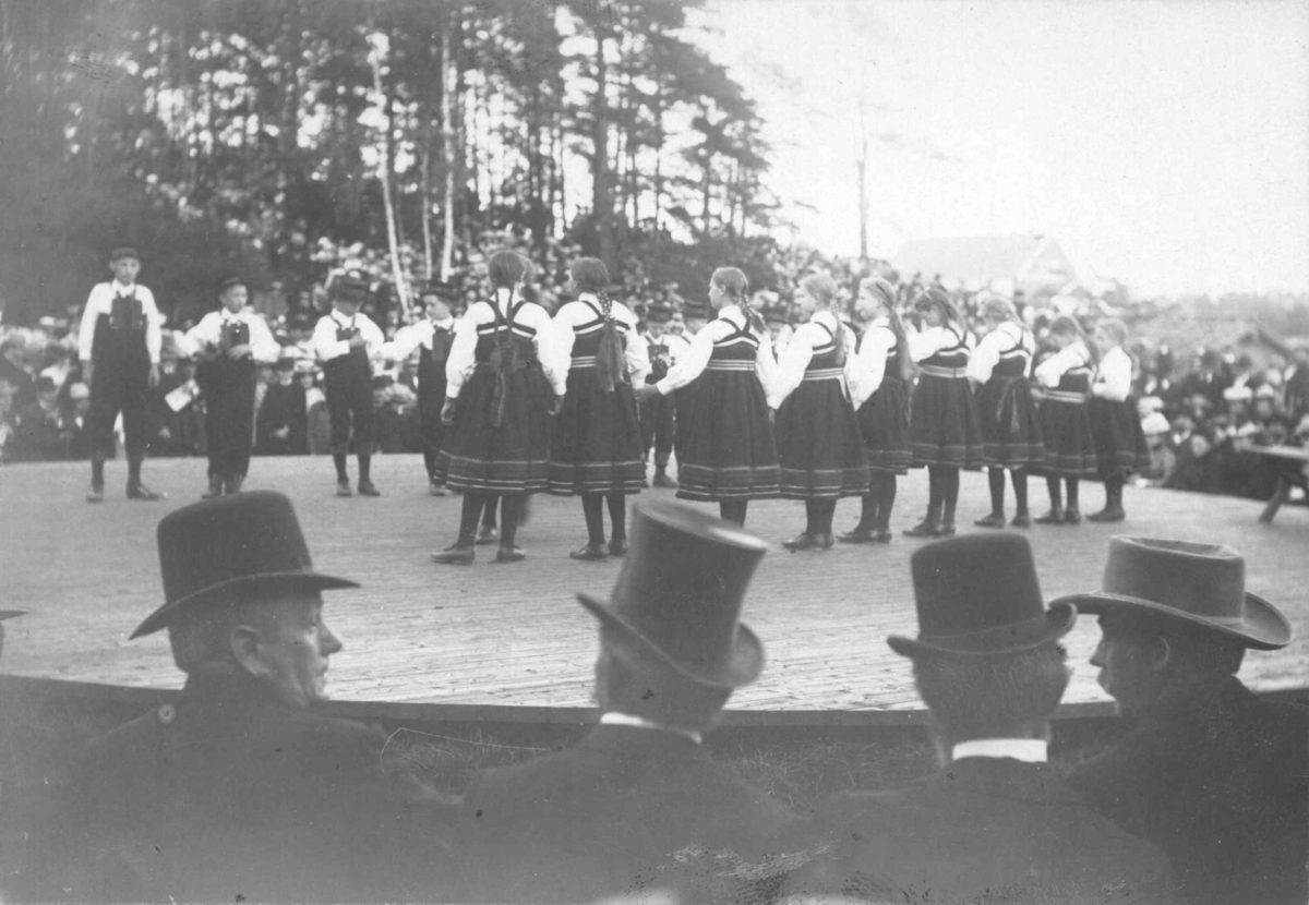 Narve Skarpmoen, Høstfest på Norsk Folkemuseum i 1902. Folkedansgruppe på Leikarvollen. Publikum med hatter og flosshatter i forgrunnen.