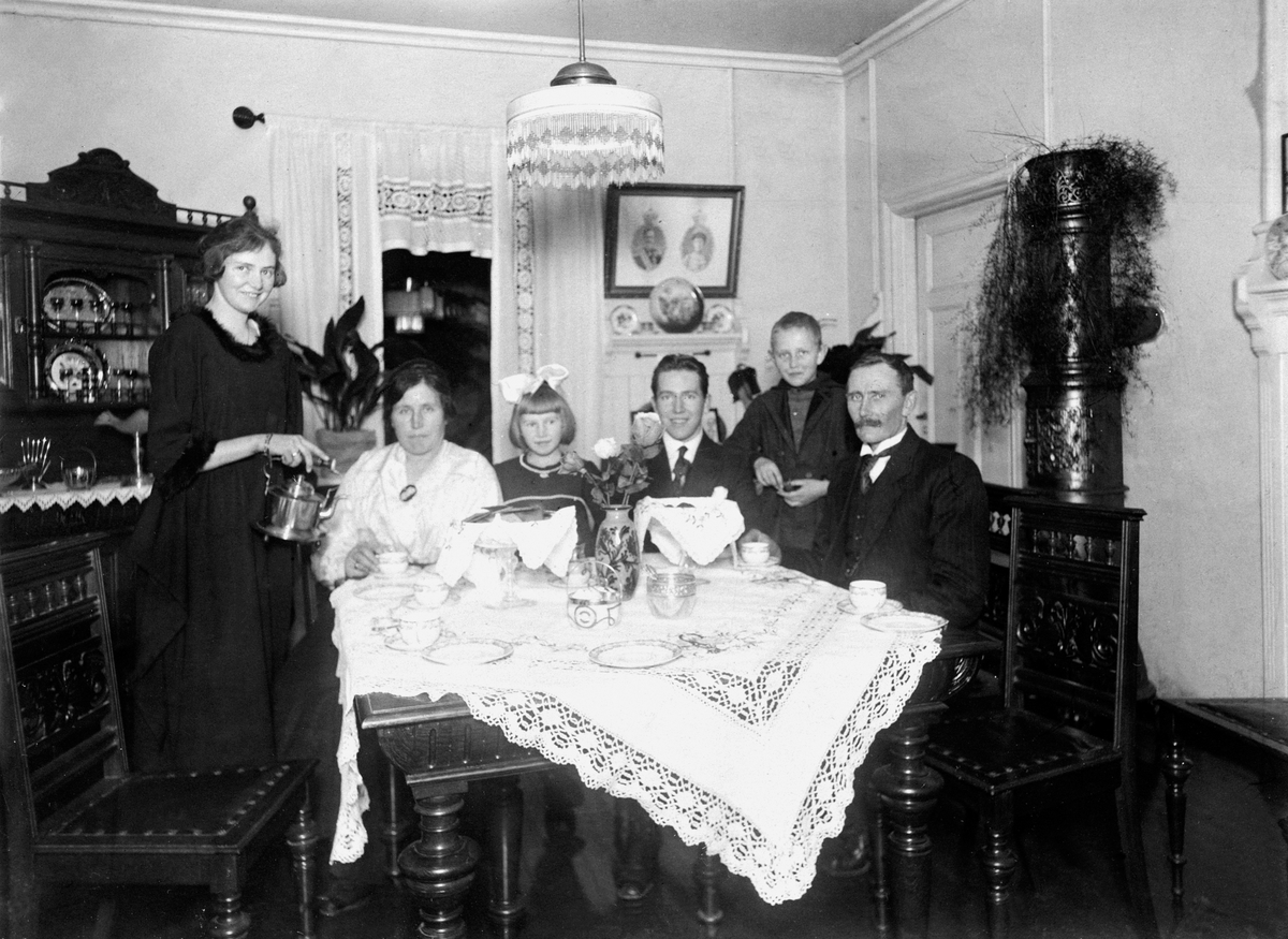 Anno Domkirkeodden, JOHAN FASTINGSGATE. INTERIØR. FAMILIEN RØST, BARN OG VOKSNE SAMLET RUNDT KAFFEBORD. F. V. CAMILLA, FRU RAGNHILD RØST, RAGNHILD ( LALLA ), GIFT WALBERG, ODBJØRN, ODVAR OG OLE RØST. CA 1920