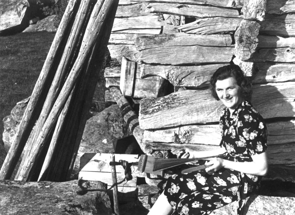 Anna Grostøl, Frk. Skott sitter ved husveggen og vever på båndvev. Rørosbygdene, Røros, Sør-Trøndelag.