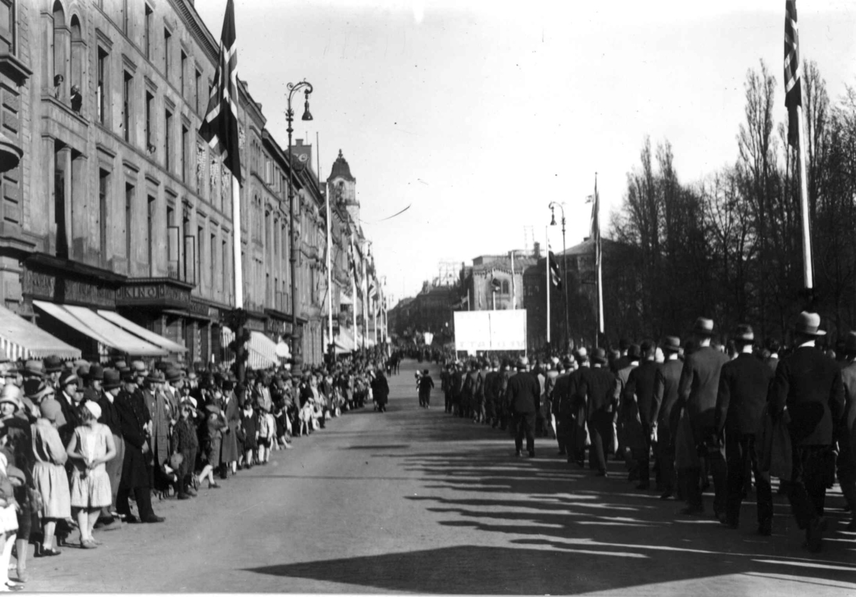 Hermann Christian Neupert, 1. mai-tog, Karl Johans gate. Toget sett bakfra. På vei mot Stortinget. Menn. Faner. Flagg.Tilskuere.