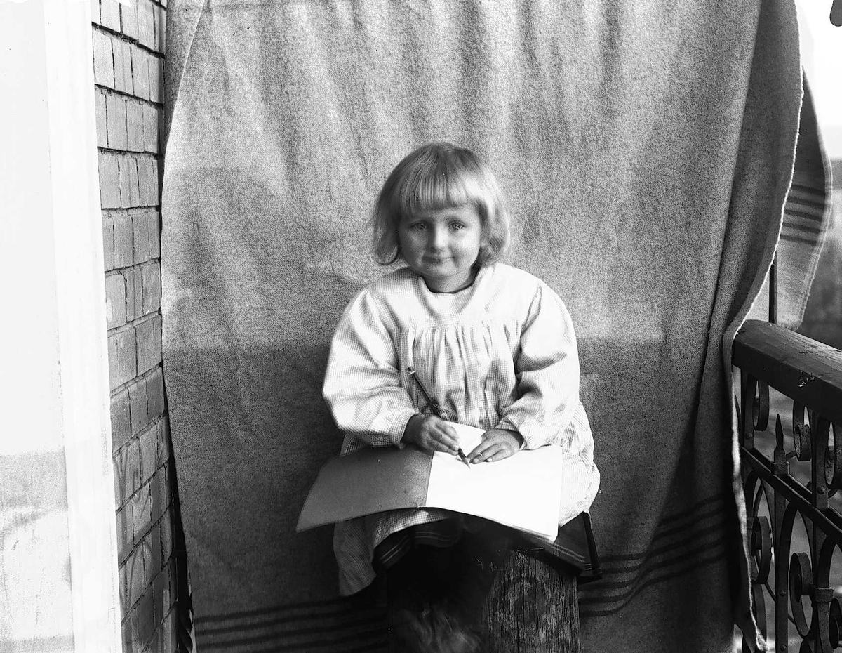 Axel Quinsgaard Wiborg, Gudrun Q. Wiborg fotografert på balkong, Oslo, 1899, mot opphengt bakteppe.