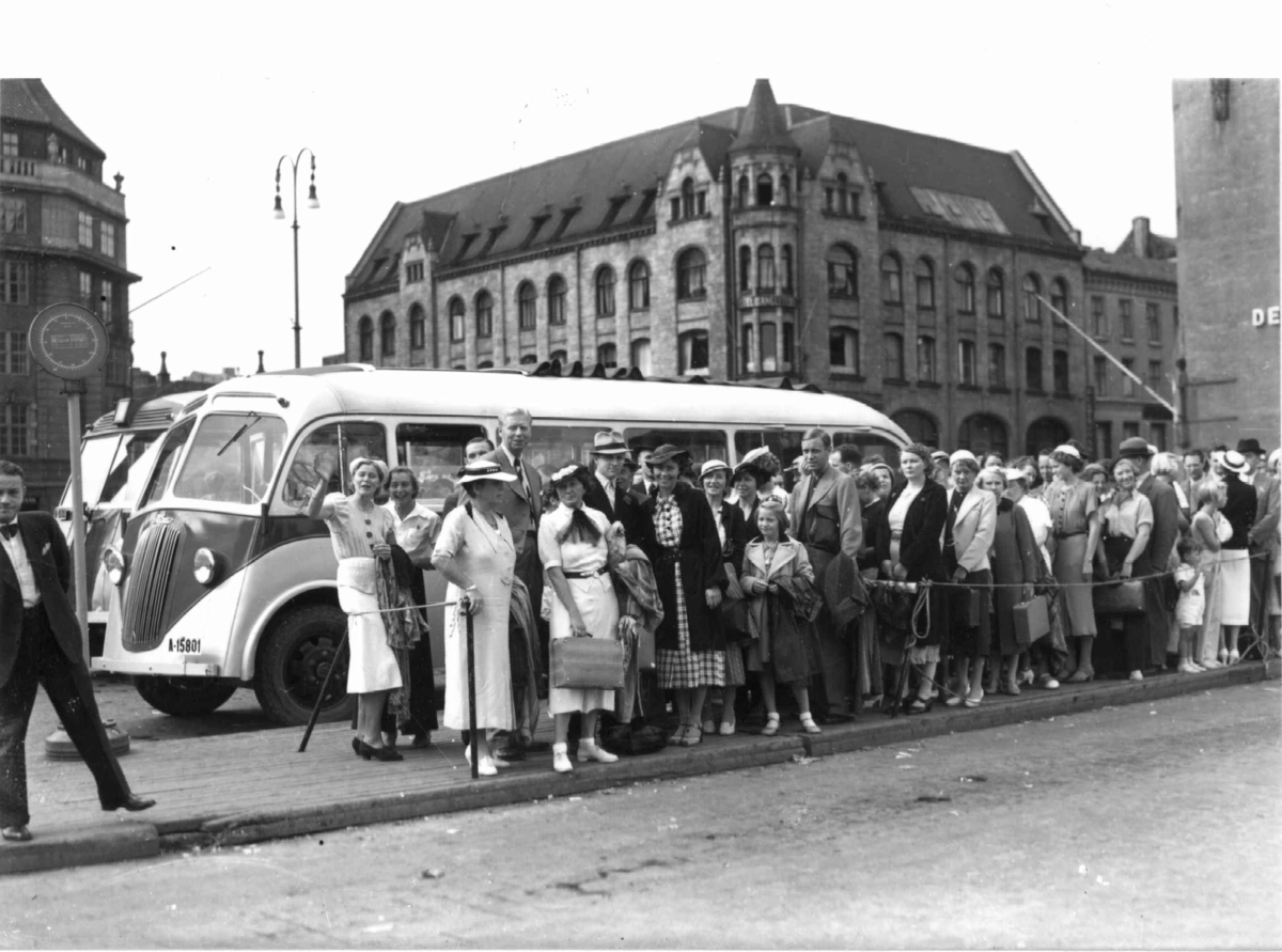 Hermann Christian Neupert, Friluftsliv. Jernbanetorget, Oslo. 1937. Kø for buss til Ingierstrand. Sommerkledde barn, kvinner og menn.