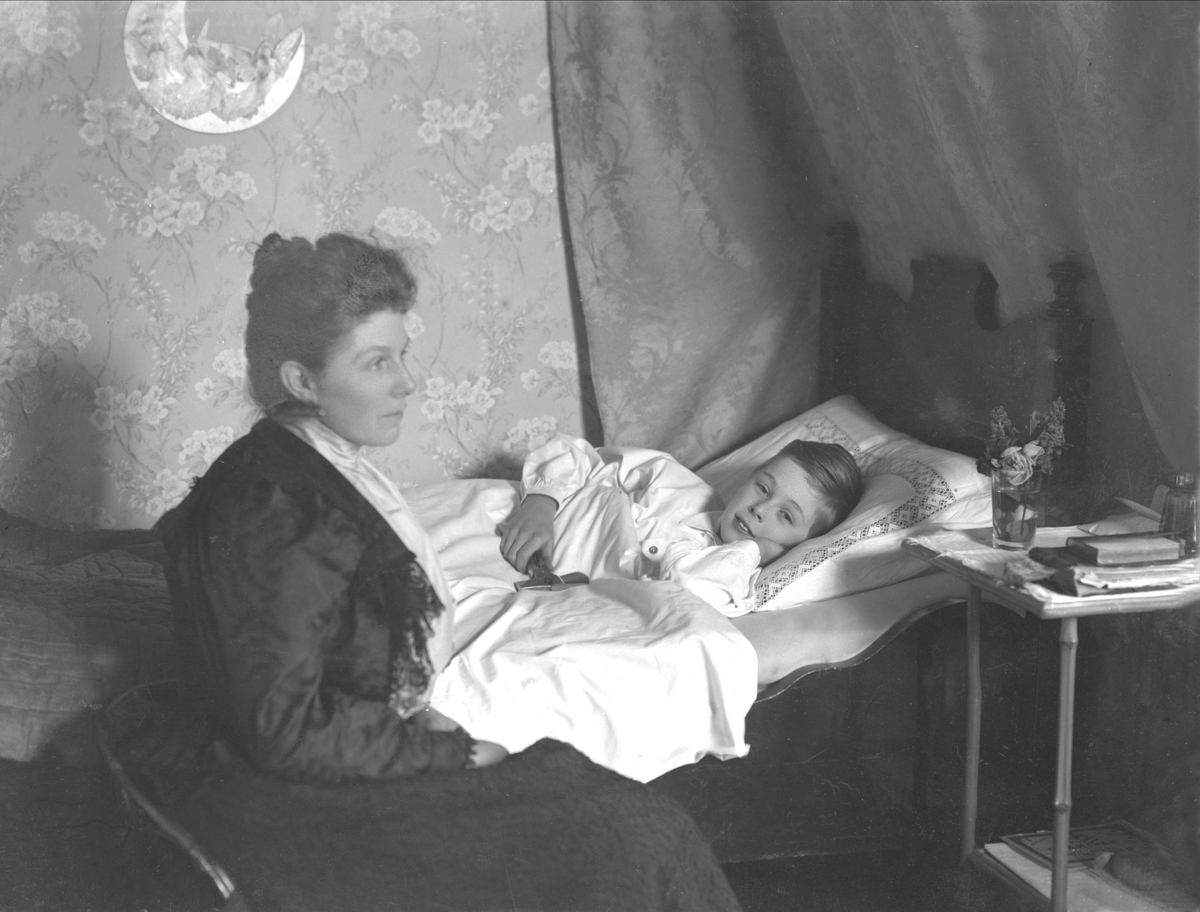 Gustav Borgen, Interiørbilde, fru kammerherre Ekeberg sittende ved barnesengen. Et barn ligger i sengen.