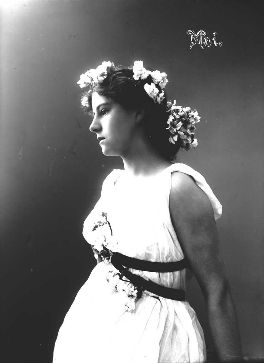 Solveig Lund, Studioportrett av kvinne i drakt med blomster i håret.